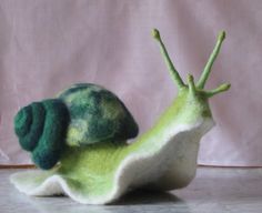 a green and white snail sitting on top of a table