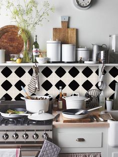 a kitchen with black and white tiles on the wall, stove top and countertop