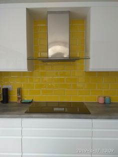 a kitchen with white cabinets and yellow tiles on the backsplash is seen in this image