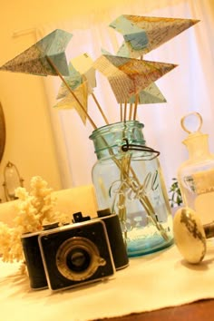 an old camera and some paper stars in a vase on a table next to a mirror