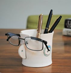 a white cup with glasses and pens in it