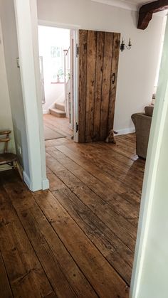 an open door in the middle of a room with wood floors and white paint on the walls