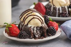 two desserts on plates with strawberries and chocolate