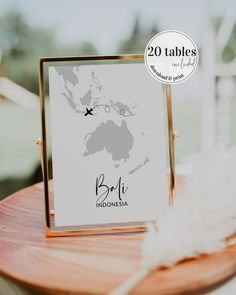 a wooden table topped with a card and a white feather on top of it next to a window