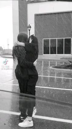 two people standing in the rain hugging each other