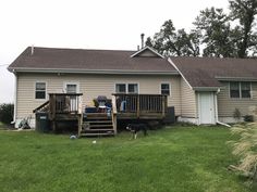 a dog standing in front of a house next to a yard with grass and trees