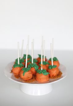 there are carrots with green leaves on top of the cake plate and white sticks sticking out of them