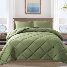 a bed with green comforter and pillows in a room