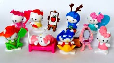 hello kitty figurines are lined up on a white surface with an easel and mirror in the background