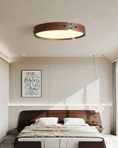 a large bed sitting under a ceiling light in a bedroom next to a painting on the wall