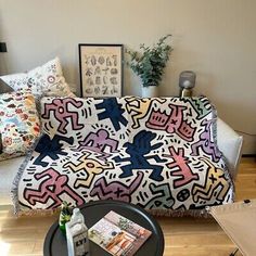 a living room with a couch covered in an abstractly designed blanket and various items