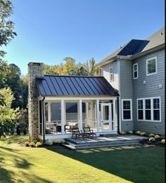 a house with a metal roof and glass doors on the front porch, surrounded by grass