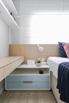 a bedroom with a bed, desk and storage drawers in the corner next to it