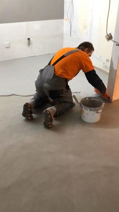 a man in an orange shirt is painting the floor