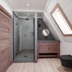 an attic bathroom with wood floors and white walls, along with a walk in shower