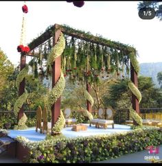 an outdoor wedding setup with flowers and greenery on the stage for guests to sit down