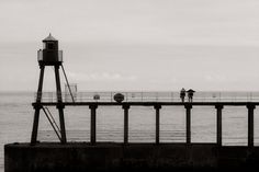 some people are standing on the pier by the water and looking out at the ocean