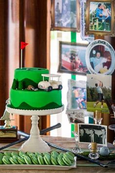 a green cake sitting on top of a table next to pictures and other things around it