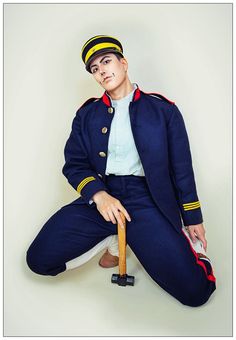 a man in uniform is sitting on the ground with a baseball bat and wearing a hat