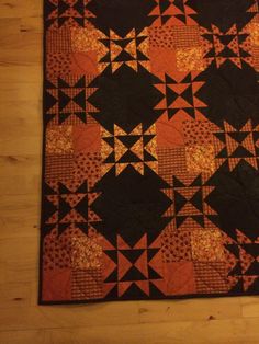 an orange and black quilt on a wooden floor