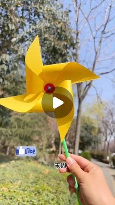 a person holding a yellow paper flower in their hand