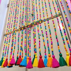 multicolored tasselled beads hanging on the side of a building with wooden poles