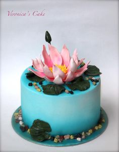 there is a blue cake with pink flowers on the top and green leaves on the bottom