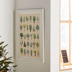 a christmas tree in front of a window with a framed art print on the wall