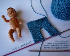 there is a small doll next to yarn and knitting needles