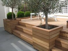 a wooden planter filled with trees on top of a patio