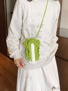 a woman in a white dress holding a green purse with a large object attached to it