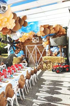 an outdoor table set up for a birthday party with balloons and farm animals on it