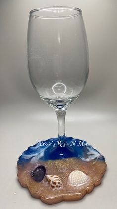 a wine glass sitting on top of a table next to a seashell and sand dollar