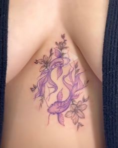 a woman's breast with flowers and fish tattoo on her stomach, which is covered in purple ink