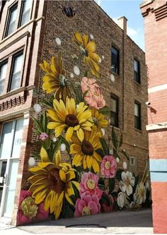 a large mural painted on the side of a brick building with sunflowers and other flowers