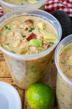 three plastic cups filled with soup next to a lime