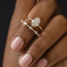 a woman's hand holding an engagement ring with diamonds on the top and bottom