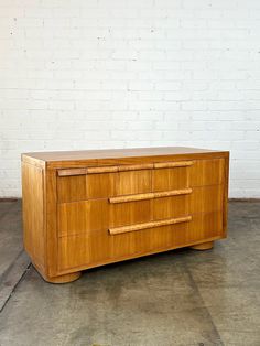 a large wooden dresser sitting on top of a cement floor next to a white brick wall