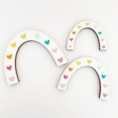 two paper cutout shapes with hearts on them, one is white and the other is multicolored