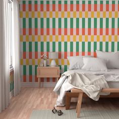 a bedroom with an orange, green and yellow striped wall paper on the wall next to a bed