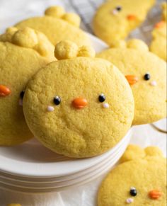 some yellow cookies with black dots and orange noses are sitting on a white plate in front of other ones