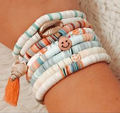 a woman's arm with bracelets on it and a smiley face charm in the middle