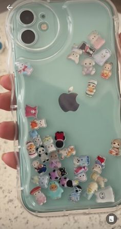 someone is holding up their phone case with many small animal stickers on the back