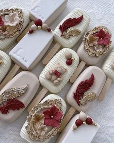 many different types of decorated cookies on wooden sticks with red bows and gold decorations,