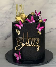 a black and gold birthday cake with pink butterflies on it's icing that says happy birthday