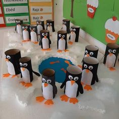 a group of penguins standing in the middle of a snow covered ground with paper cups