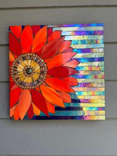 a colorful flower painted on the side of a building with multi - colored paint and wood planks