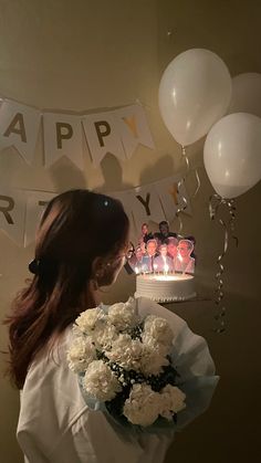 a woman standing in front of a birthday cake with candles on it and balloons around her