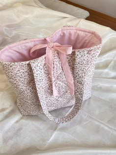 a pink and white bag sitting on top of a bed