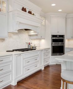 a large kitchen with white cabinets and wood flooring, along with an island in the middle